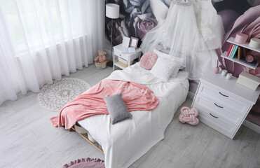 Teenage girl's room interior with comfortable bed and floral wallpaper. Idea for stylish design © New Africa