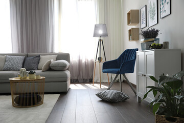 Elegant living room with comfortable sofa and armchair near window. Interior design