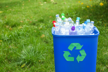 Many used bottles in trash bin outdoors, space for text. Plastic recycling