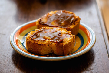 pan tostado con manteca y dulce de leche con luz de mañana sobre plato de colores  comida típica rústica y tradicional argentina