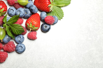 Mix of fresh berries on light table, flat lay. Space for text