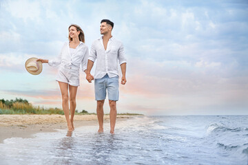 Happy couple having romantic walk on beach. Space for text