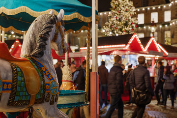 Selective focus at horse carousel and blur background of night illuminated atmosphere of...