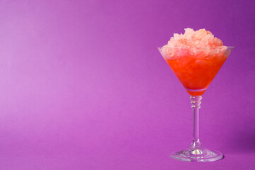 Shaving ice in martini glass on violet background, space for text