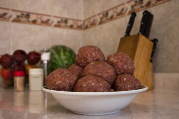 Raw meatballs inside the plate in the kitchen