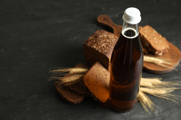 Bottle of delicious fresh kvass, spikelets and bread on grey table, closeup. Space for text