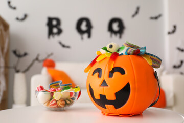 Halloween trick or treat bucket and many different sweets on white table indoors