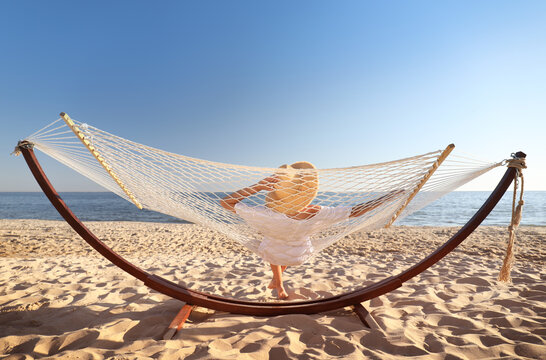 Young woman relaxing in hammock on beach