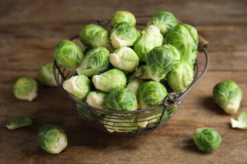 Metal basket with fresh Brussels sprouts on wooden table, closeup