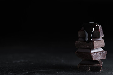 Delicious dark chocolate with syrup on black table. Space for text