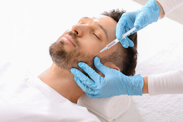 Bearded man getting beauty injection in face in luxury salon