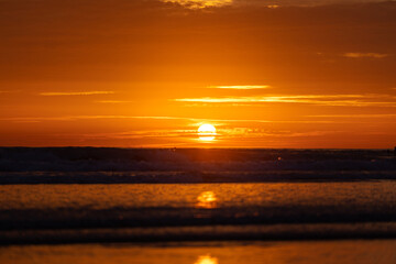 Obraz premium Silhouette-blurred background of beach during dramatic sunset with orange burning sky. High contrast and vibrant ratio photo.