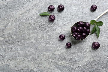 Fresh acai berries and spoon on light grey table, flat lay. Space for text