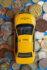 yellow taxi car on metal coins  background.  Cash.