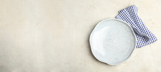 Empty plate and napkin on light table, top view