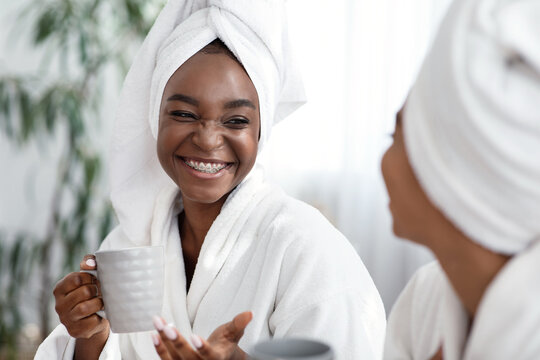 Two Young African Women Joking While Drinking Tea