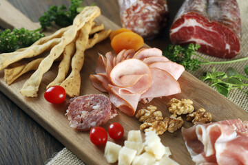 Cheese, parma ham, salami, sirloin, sausage with olives and spices on wooden board