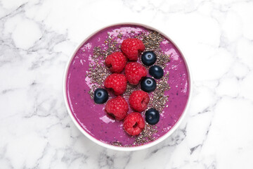 Delicious acai smoothie with raspberries and chia seeds on white marble table, top view