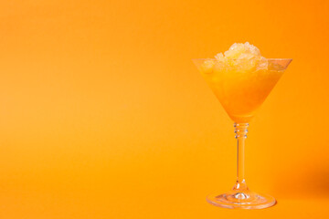 Shaving ice in martini glass on orange background, space for text