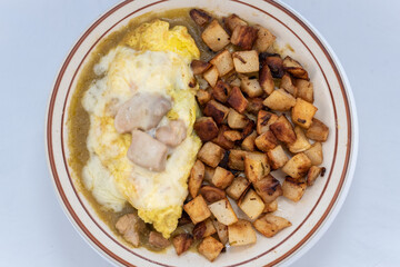 Overhead view of generous serving meal of a hearty chili verde covered in green sauce combined with eggs and potatoes