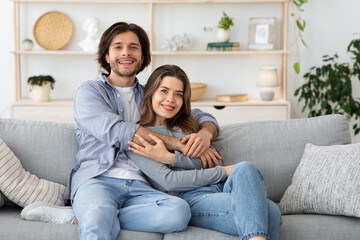 Happy married couple hugging on couch at home