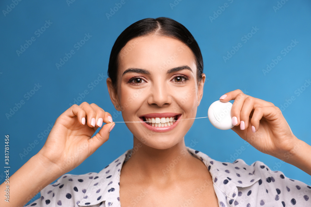 Poster Young woman flossing her teeth on blue background. Cosmetic dentistry