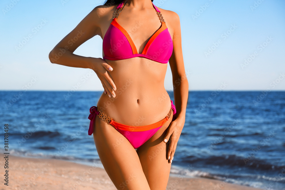 Poster woman in pink stylish bikini on beach, closeup