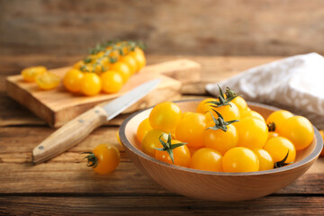 Ripe yellow tomatoes in bowl on wooden table