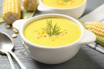 Delicious creamy corn soup served on grey wooden table