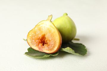Whole and cut tasty fresh green figs with leaf on white table, closeup