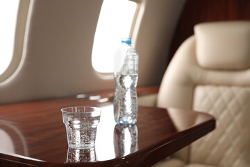 Glass and bottle with water on plane. Comfortable flight
