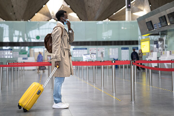 Black man with suitcase wearing face protective mask during virus epidemic, covid-19 pandemic while...