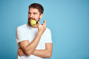 An energetic man with a green apple on a blue background gestures with his hands Copy Space emotions