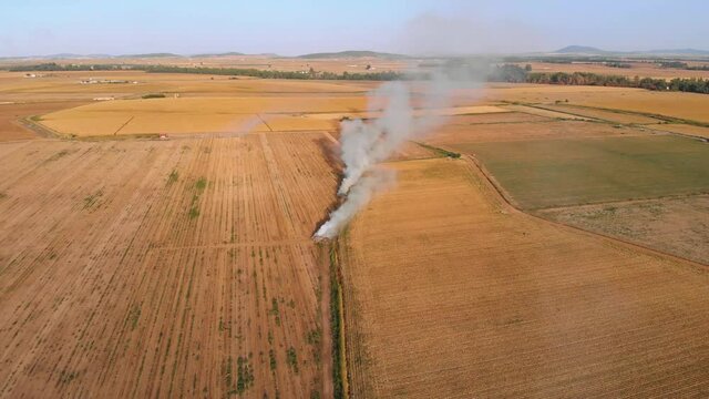 Aerial footage zooming out of a very close stubble fire. Little by little the image reveals the smoke of another great bonfire.