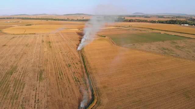 Aerial footage zooming out of a very close stubble fire. Little by little the image reveals tanother great bonfire.