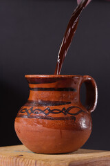 Serving hot coffee in clay jar with black background