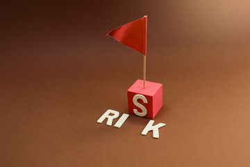 Block letters on risk with red flag pierced on the red cube
