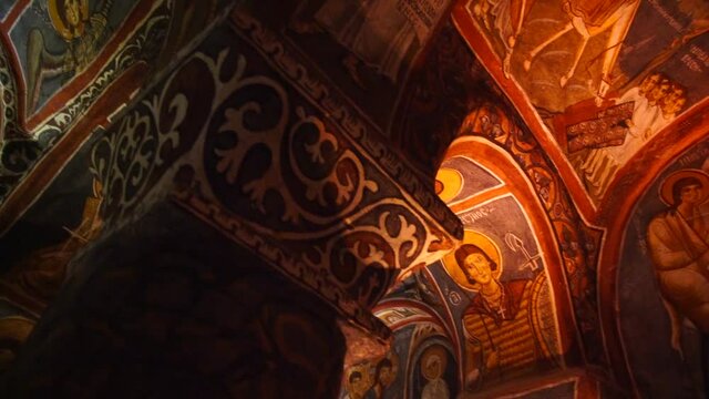 Cave cathedral religious christian mural art in Goreme open air museum in Cappadocia, slow motion, fresco paintings in ancient dark church of byzantine era