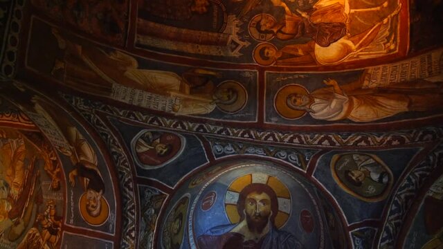Cave cathedral religious christian mural art in Goreme open air museum in Cappadocia, slow motion, fresco paintings in ancient dark church of byzantine era