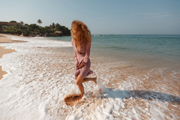 Young woman have fi on the beach, run and make splashes, hair on her face