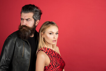 Portrait of a young elegant couple. Sensual young woman and her bearded lover. Fashion couple on red.