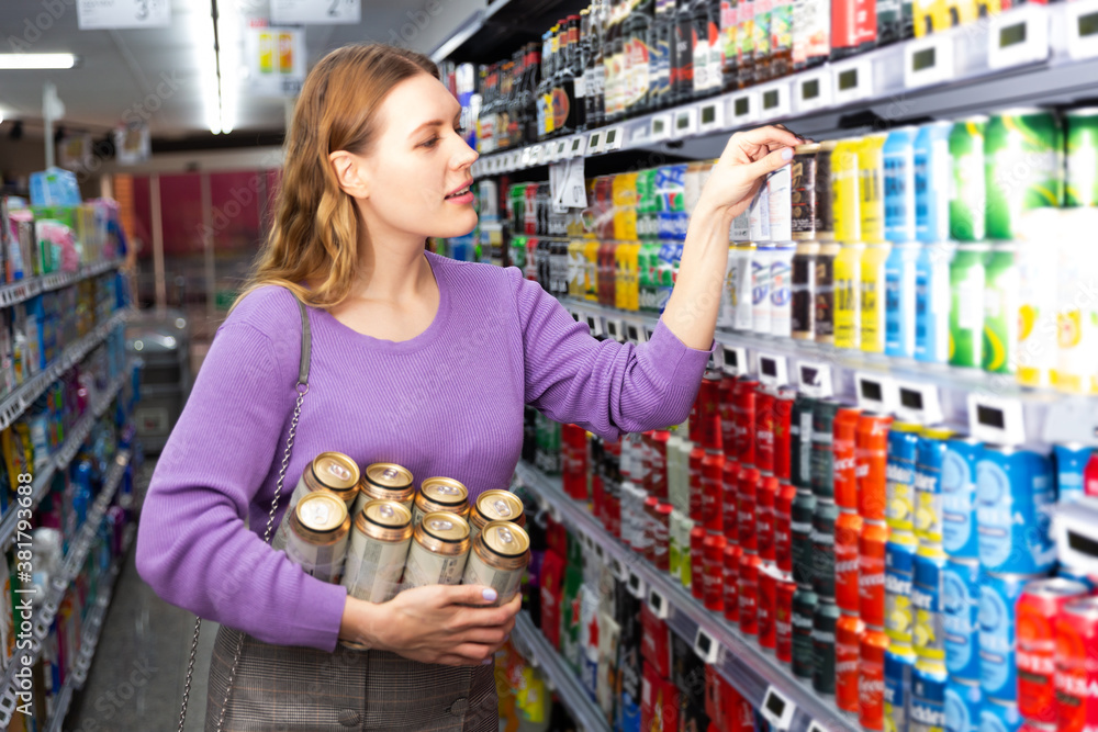 Wall mural portrait of nice female customer choosing beer in hypermarket