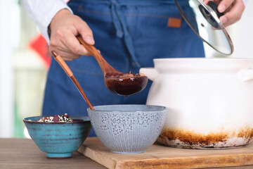 People wearing apron in the kitchen put the boiled Laba porridge into the bowl