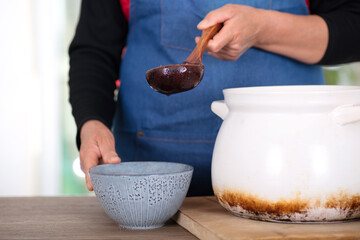 People wearing apron in the kitchen put the boiled Laba porridge into the bowl