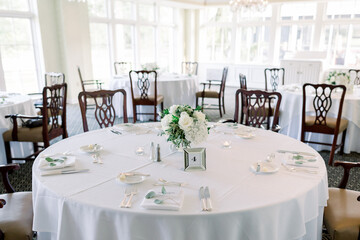 Close-up of a simple wedding reception table with one flower arrangement in a vase. 