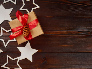 New Year's composition. Gift box with red ribbon, decorative stars on dark wooden background