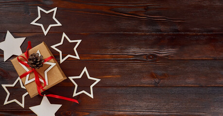 Fototapeta na wymiar New Year's composition. Gift box with red ribbon, decorative stars on dark wooden background