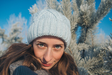 portrait of a beautiful girl in a hat on the background of the snow landscape in the cold season. winter walking. snowy weather