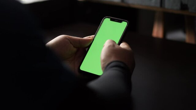 Close up and slide movement of a man using a smartphone. Chroma key green screen on the smartphone screen. A man scrolls information on the phone screen.