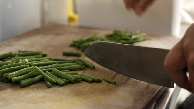 Slow-motion and zoom in the movement of Asian chef cutting green bean in the kitchen.